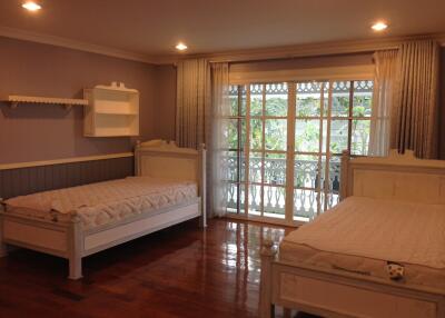 Spacious bedroom with two beds, large window, and wooden flooring