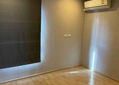 Empty bedroom with wooden floors, window with a dark curtain and a split air conditioning unit