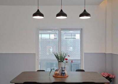 Modern dining area with table and chairs, featuring pendant lighting