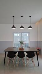 Modern dining area with table and chairs, featuring pendant lighting