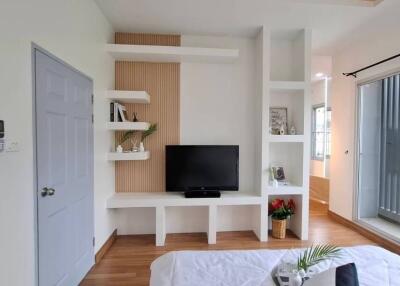 Modern bedroom with a TV, shelves, and balcony access