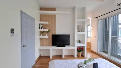 Modern bedroom with a TV, shelves, and balcony access