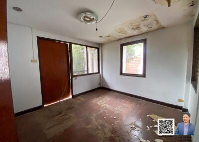 Room with damaged ceiling and floor, two windows, and door