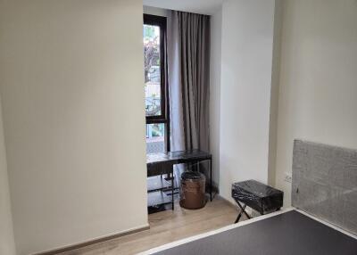 A bedroom with a window, desk, and stool