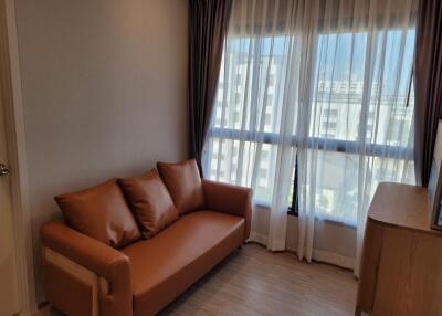 A cozy living room with a brown leather sofa and large windows.