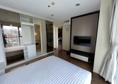 Modern bedroom with striped bed, large closet, and TV mounted on the wall