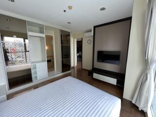 Modern bedroom with striped bed, large closet, and TV mounted on the wall