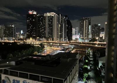 Nighttime cityscape featuring illuminated buildings, highway, and streets.