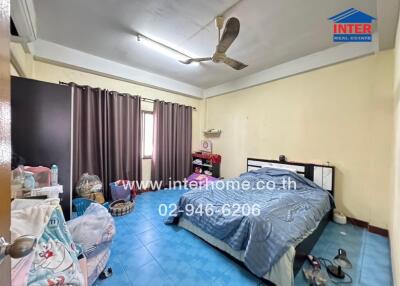 A bedroom with a bed, ceiling fan, curtains, and various personal items