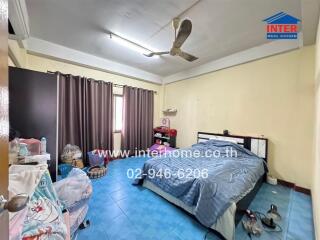 A bedroom with a bed, ceiling fan, curtains, and various personal items