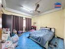 A bedroom with a bed, ceiling fan, curtains, and various personal items