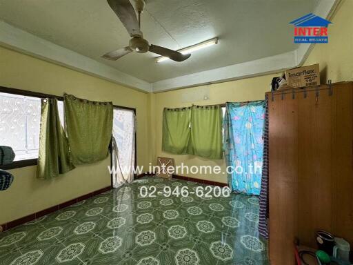 Bedroom with green drapes, ceiling fan, patterned tile flooring, and storage cabinet