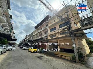 Street view of residential buildings showing multiple levels and parked cars