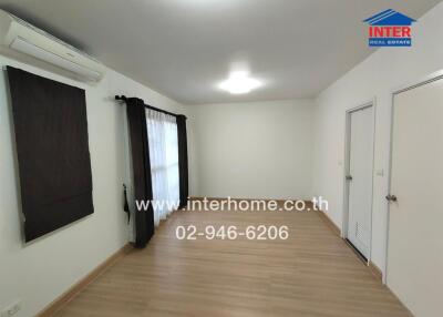 Living room with wooden flooring and large window with curtains