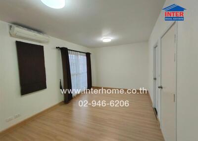 Spacious empty living room with large window, wooden floor, and air conditioning