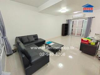 Modern living room with black leather sofa and glass coffee table