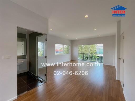 Spacious living room with wooden flooring and large windows