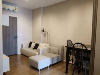 Living room with sofa, table, chairs, and wall-mounted air conditioner