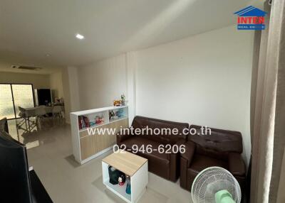 Living room with brown sofa, small coffee table, and partition showcasing decorative items