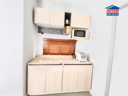 Compact kitchen area with cabinets, microwave, and rice cooker