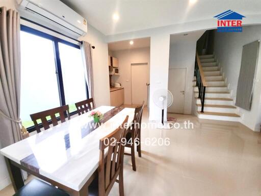 Bright dining area with a window, modern decor, and adjacent stairs.