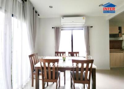 Bright dining room with a dining table and chairs, air conditioner, and large windows with curtains