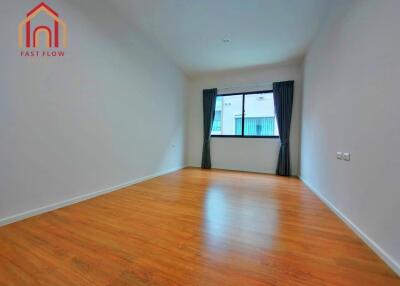 Empty bedroom with wooden floor, large window, and curtains