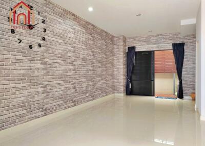 Spacious empty living room with brick wall, large clock, and sliding door