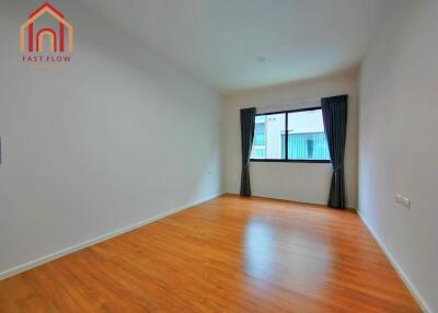 Spacious empty bedroom with wooden flooring and a large window.