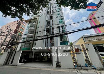 Exterior view of a multi-story residential building with surrounding infrastructure and overhead electric lines