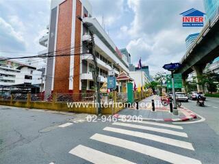 Street view of a building with road signs and logo of real estate company