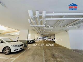 Parking garage with parked cars and visible piping on the ceiling