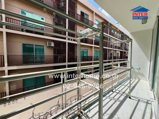 Apartment balcony with metal railings and view of neighboring building