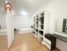 Modern bedroom with wooden flooring, a large shelving unit, and a bed