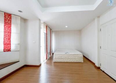 Spacious bedroom with hardwood floors and large windows