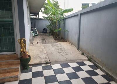 An outdoor area with checkered tiles, a small garden, and some decorative statues