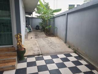 An outdoor area with checkered tiles, a small garden, and some decorative statues