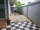 An outdoor area with checkered tiles, a small garden, and some decorative statues