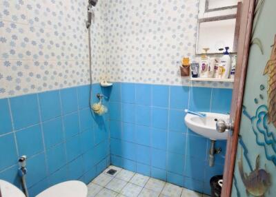 Small bathroom with blue tiles, toilet, sink, and shower