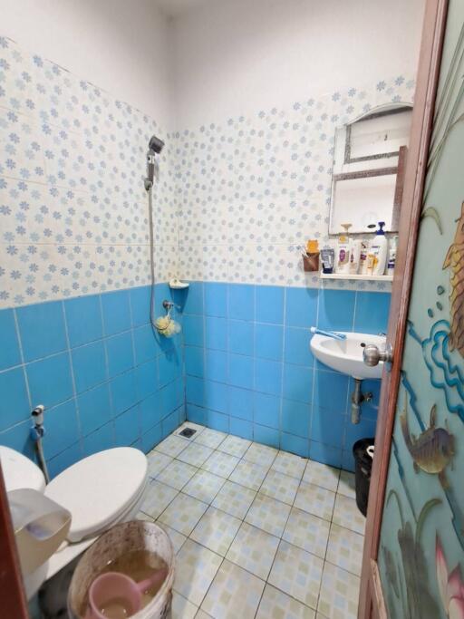 Small bathroom with blue tiles, toilet, sink, and shower