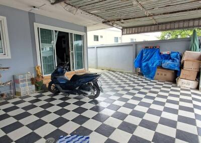 Covered garage area with checkered tiles and various stored items