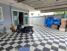 Covered garage area with checkered tiles and various stored items