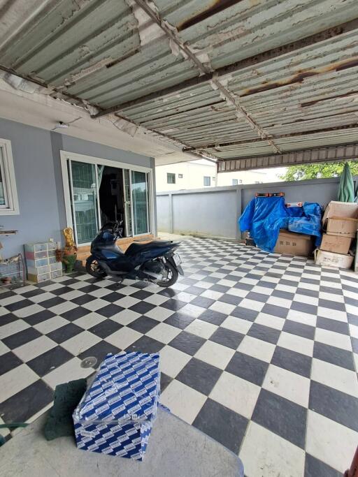 Covered garage area with checkered tiles and various stored items