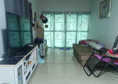 A cozy living room with various furnishings and a large window with curtains.