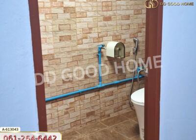 Bathroom with brick-like tile walls, toilet, and blue piping