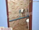 Bathroom with brick-like tile walls, toilet, and blue piping