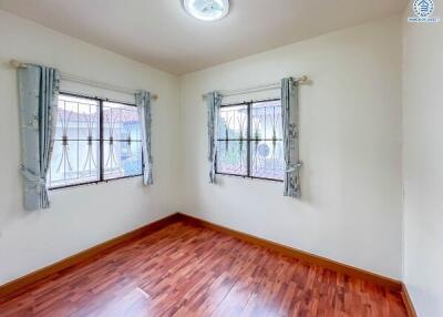 Spacious bedroom with wooden flooring and large windows