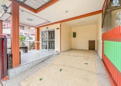 Covered entrance space with tiled flooring, door, and outside view.