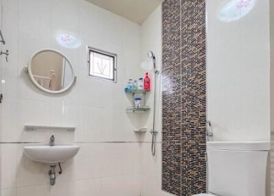 Modern bathroom with toilet, sink, wall-mounted mirror, and shower area