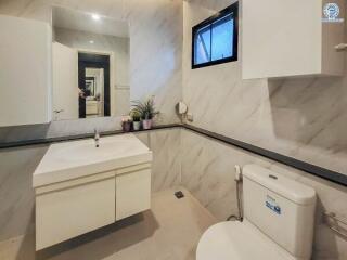 Modern bathroom with a vanity, toilet, and decorative plants